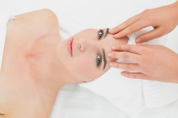 Hands massaging womans forehead at beauty spa