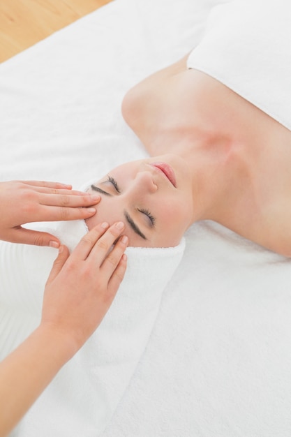 Hands massaging womans forehead at beauty spa