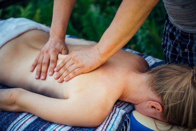 Hands of masseur on the back of patient closeup