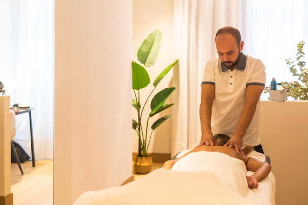 Hands of a masseur performing a massage on the table to a client on the back