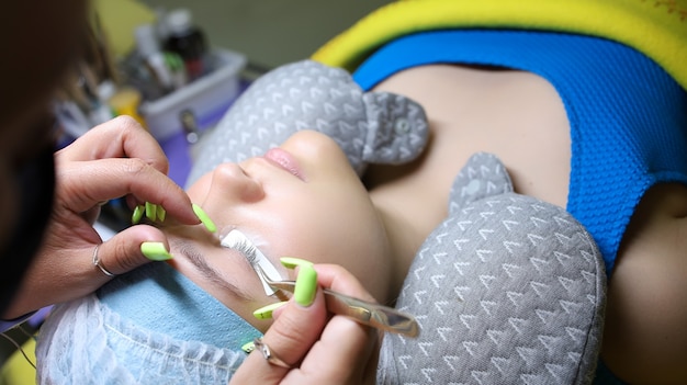 Hands of the master close-up on eyelash extension glues patches under the eyes in preparation for the procedure