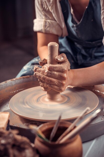 Hands of the master potter and vase of clay on the potter's wheel close-up. Master crock. Twisted potter's wheel.