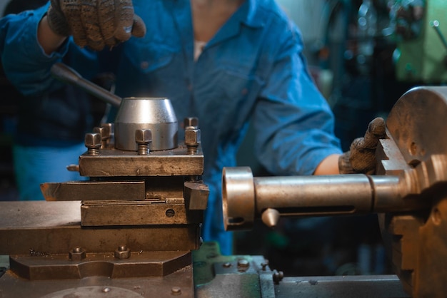 Hands of the master rotate the handle on the lathe