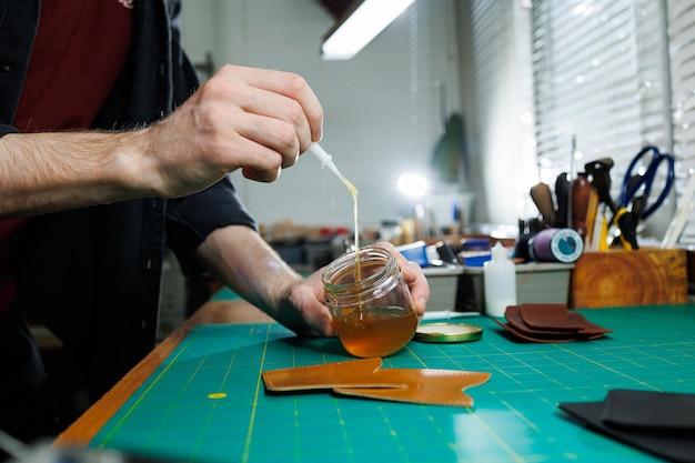 The hands of the master sew handmade leather products Men's hands connect the parts creating quality leather accessories Working process in a leather workshop