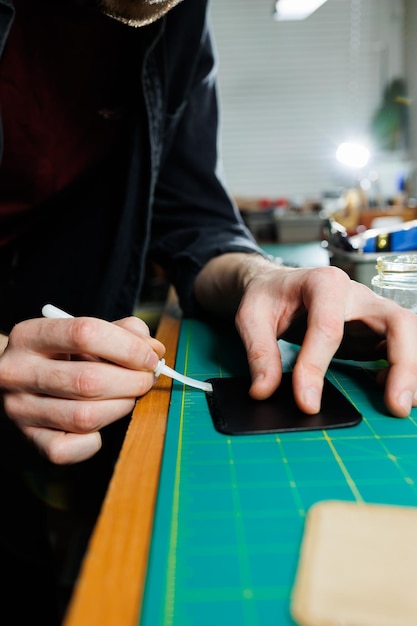 The hands of the master sew handmade leather products Men's hands connect the parts creating quality leather accessories Working process in a leather workshop