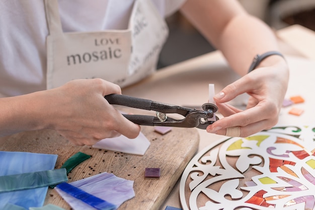 Mani del maestro che lavorano al nuovo mosaico colorato moderno. avvicinamento