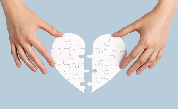 hands matching two parts of puzzle heart isolated on white