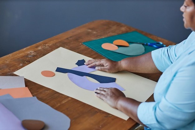 Hands of mature african american craftswoman creating composition