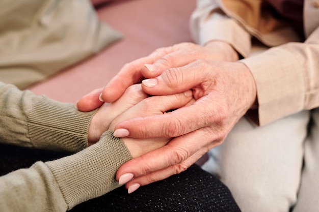 Hands of mature and young females during support