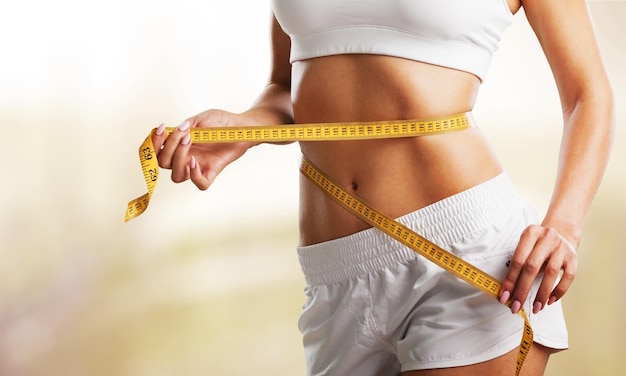 hands measuring waist with a tape. fit and healthy woman