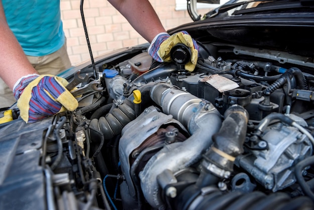 Hands of mechanics in protective gloves with car engine close up