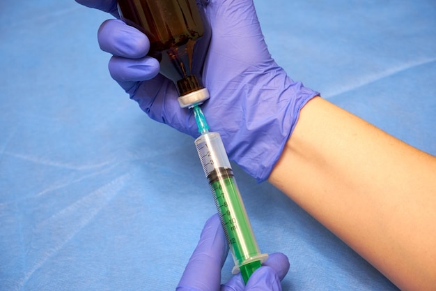 Photo hands of a medic in gloves filling a syringe closeup