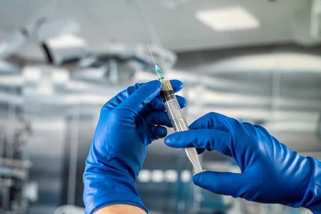 Hands of medical assistant wear gloves and preparing syringe for inject anesthesia preparing for surgery in the surgical office at the hospital