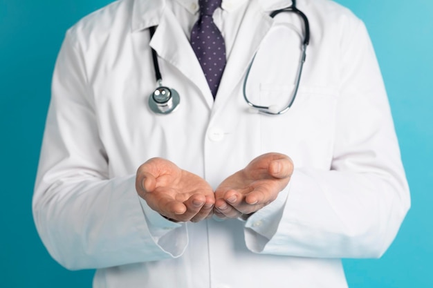 Hands of medical doctor with a stethoscope isolated on blue