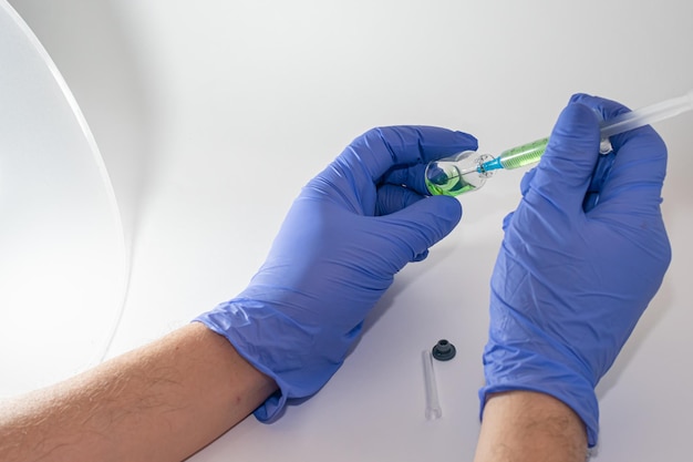 Hands in medical gloves hold a bottle with a vaccine on a white background