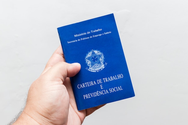 Mani di uomo di mezza età che tengono il libro di lavoro, documento di sicurezza sociale brasiliano