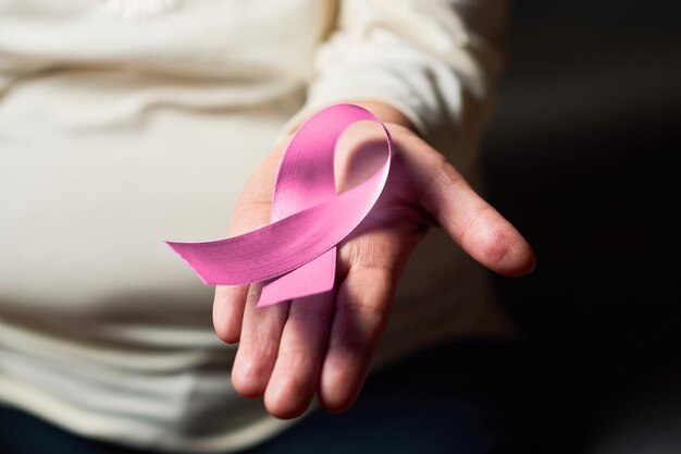 Hands of middle aged woman holds pink ribbon on breast cancer day Breast cancer awareness