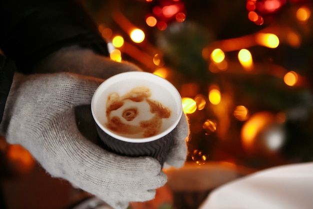 Hands in mittens hold a hot cup of coffee Coffee to go in winter