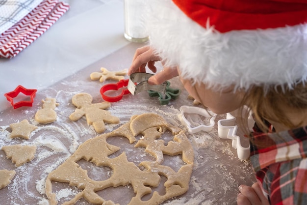 The hands of mom and daughter closeup cut out cookies from the dough with molds on a Christmas theme in the form of a snowman a Christmas tree stars