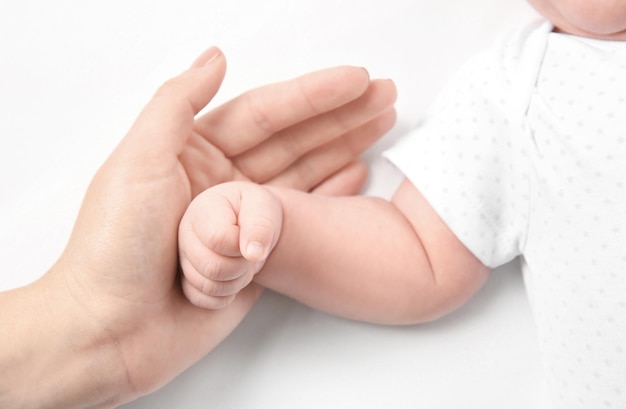 Hands of mother and cute newborn baby on white background