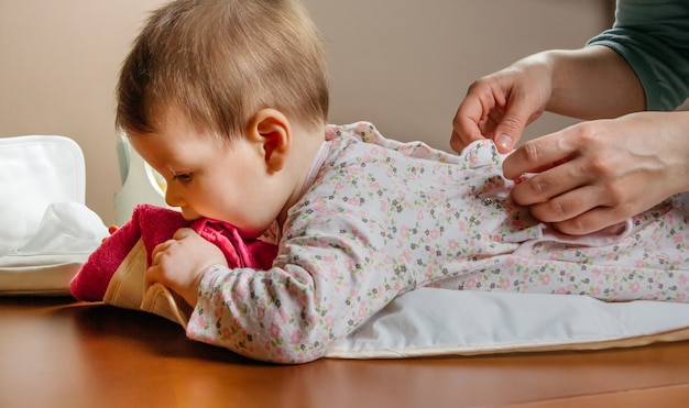 Photo hands of mother dressing her baby lying down after the change of diaper