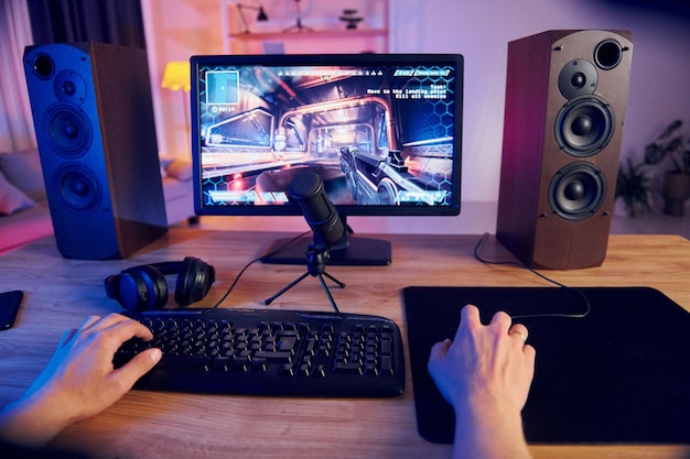 Hands on the mouse and keyboard online streamer playing fps shooter game at home