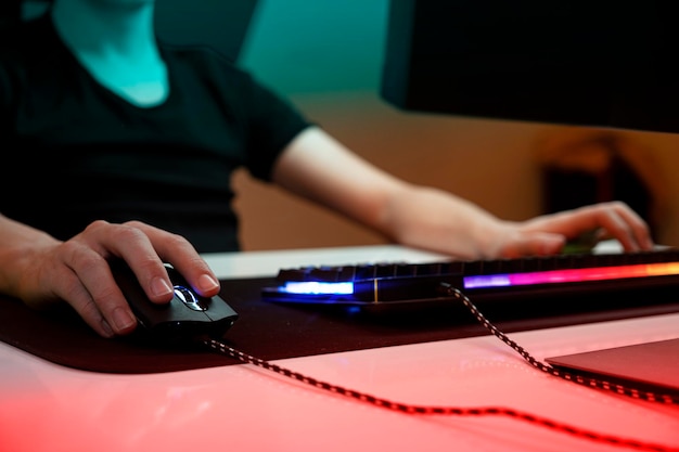 若いゲーマーにマウスの選択的焦点を当てる夜、彼の暗い部屋で一人でマウスを手にする