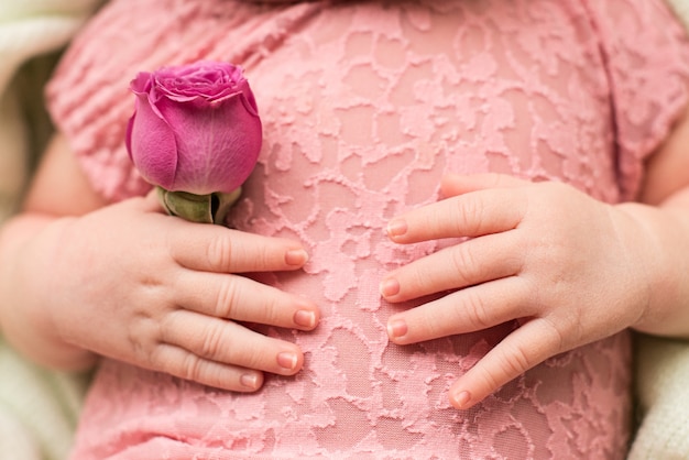 Foto mani del neonato con la rosa di rosa del fiore. dita, cure materne, amore e famiglia, tenerezza.