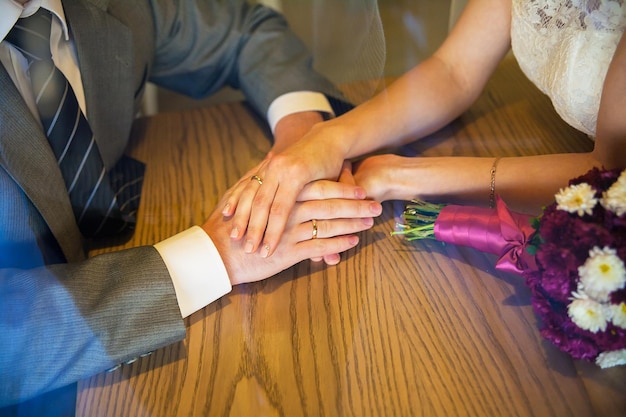 Photo hands newlyweds hold and sit in a cafe