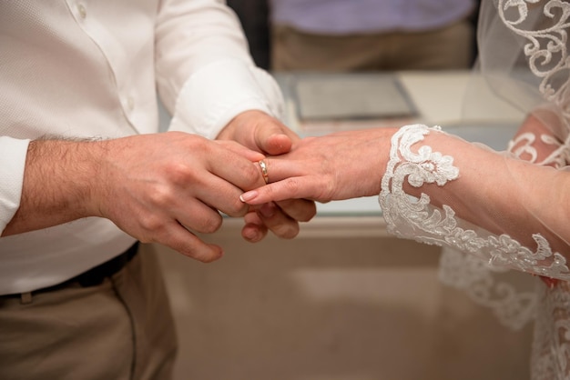 Hands of the newlyweds at the wedding ceremony of dressing the wedding rings