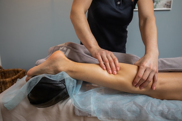 Фото Руки мастера женского массажа делает расслабляющий массаж ног для молодой женщины крупным планом. массажист месит икроножную мышцу клиента