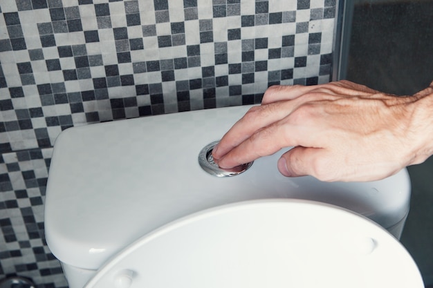남자의 손, 물 버튼을 누르고, 화장실, 건강 개념을 내리십시오.