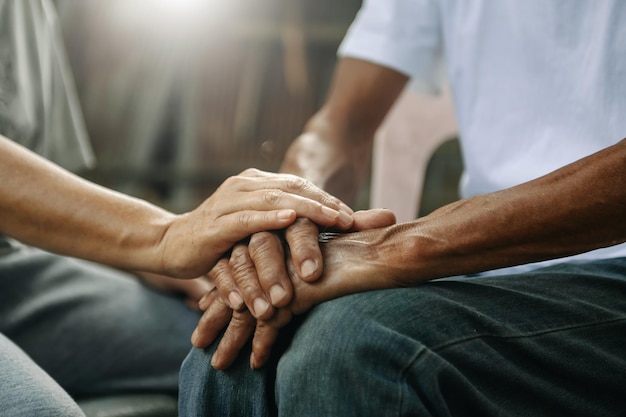 Photo hands of the old man and a woman hand on the wood table