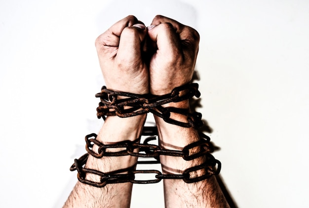 古いさびた鎖の手。白い背景で隔離。罠にかかった男。奴隷の概念。