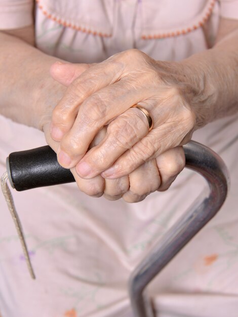 Hands of old woman on a cane
