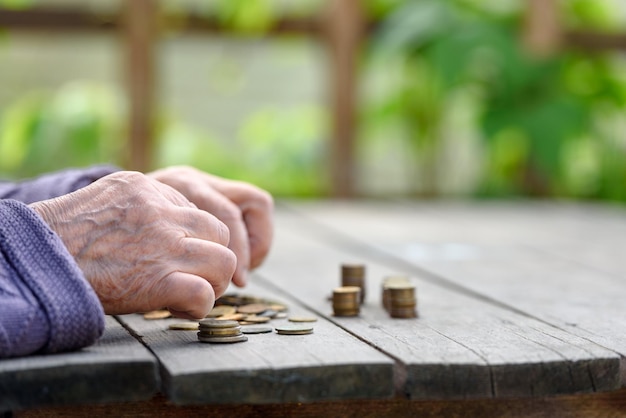 Руки старухи пересчитывают монеты на деревянном столе