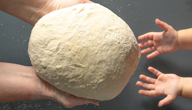 Hands of old woman transmit bread dough to small hands of girl The intergenerational connection