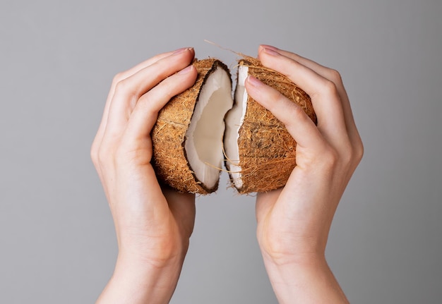 Hands opening coconut two pieces halves of coco nut fruit in brown shell