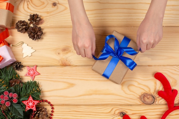 Hands packing Christmas gift on wooden