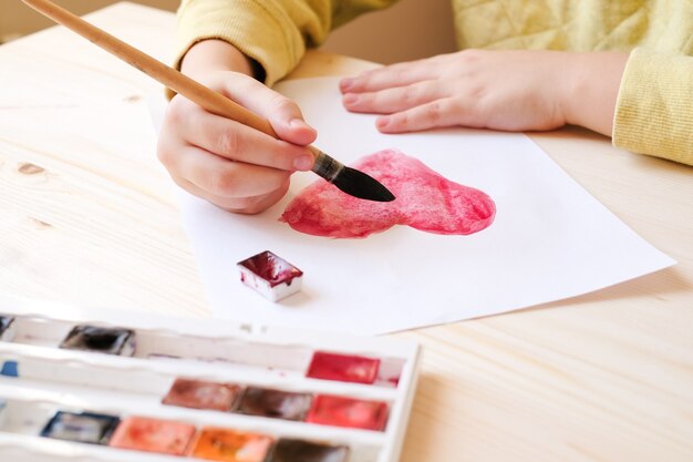 Hands paint watercolor hearts for valentine day