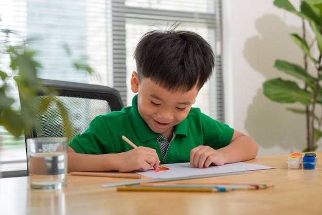 小さな男の子と創造性のためのテーブルを描く手