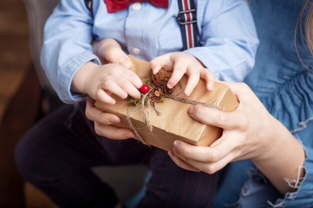 Mani del genitore e del bambino che tengono una confezione regalo di natale.