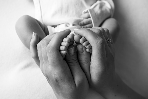 Hands of parents. The legs, feet of the newborn in the hands of mom and dad. High quality photo