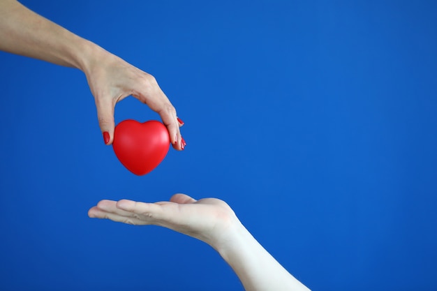 Hands pass red heart heart disease concept