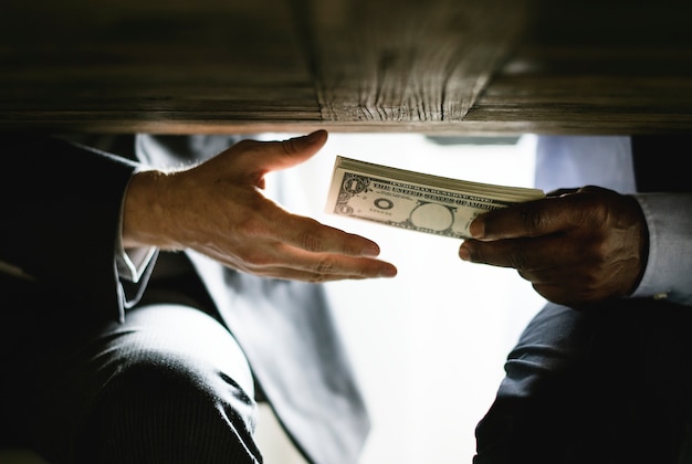 Photo hands passing money under table corruption bribery