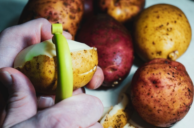 Hands peeling potatoes with peeler