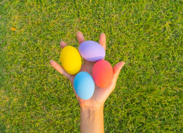 Foto mani di persone che tengono colorate uova di pasqua sullo sfondo dell'erba verde naturale decorazione alimentare in vacanza