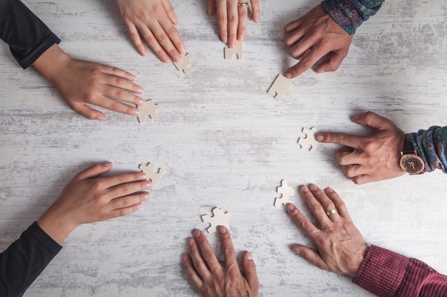 Mani di persone che tengono puzzle. partnership, successo, lavoro di squadra