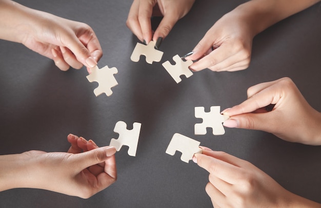 Hands of people holding jigsaw puzzle partnership