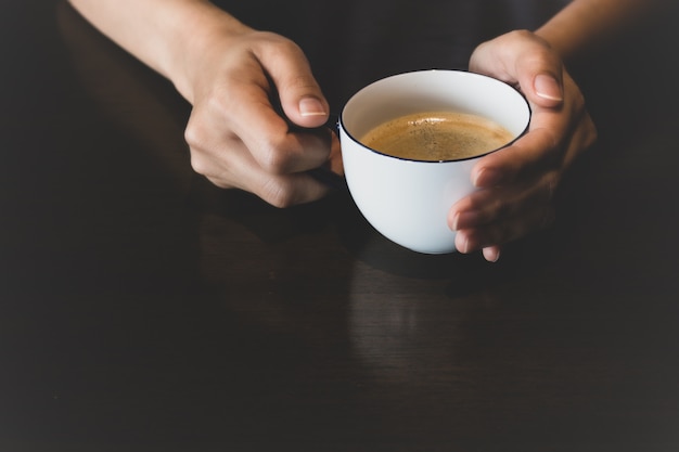 Mani di una persona che tiene tazza di caffè